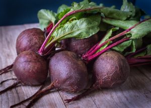 A close-up of.a bunch of red beets on a wood table
