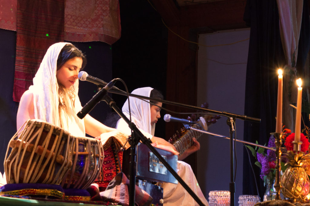 Yogic singers on stage with cabalas and female sitar player to her right