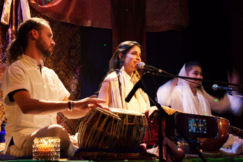 Yogic singer on stage with male tabala player on her left and female sitar player to her right